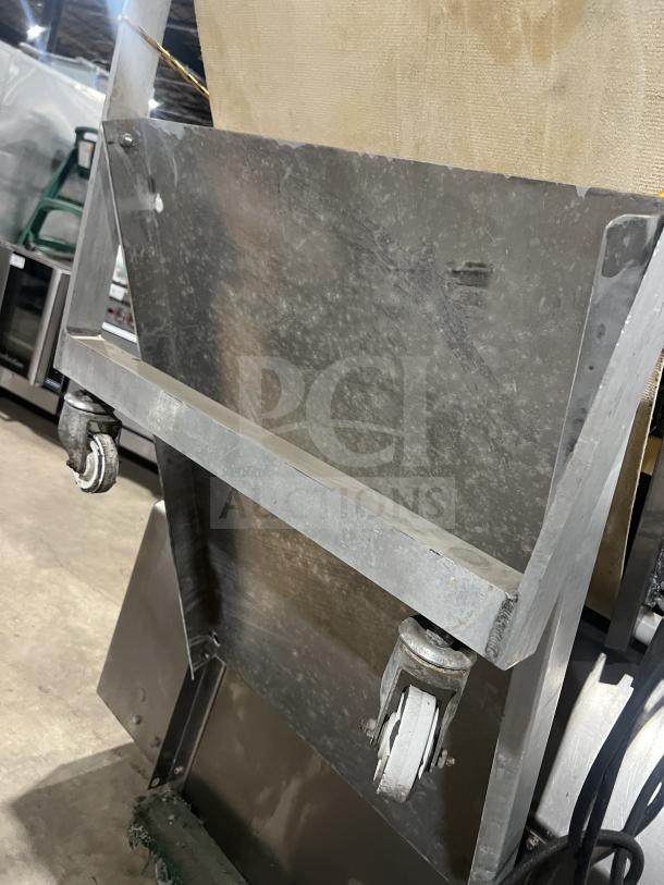 Moline commercial reversible dough sheeter, floor style, heavy-duty with foot pedal, steel frame, visible wear, caster wheels.