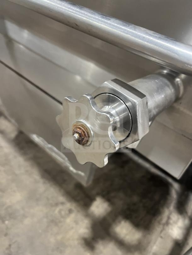 Commercial stainless steel braising pan with tilting feature, shown on legs. Close-up of tilting mechanism handle.