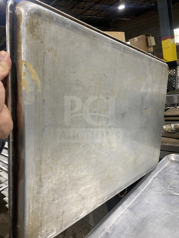 Commercial stainless steel baking sheet pan in used condition, showing surface wear and light discoloration; durable for heavy-duty use.