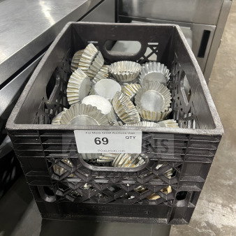 Crate of tin-plated tartlet molds on countertop; label "69 QTY" from PCIauctions.com visible.