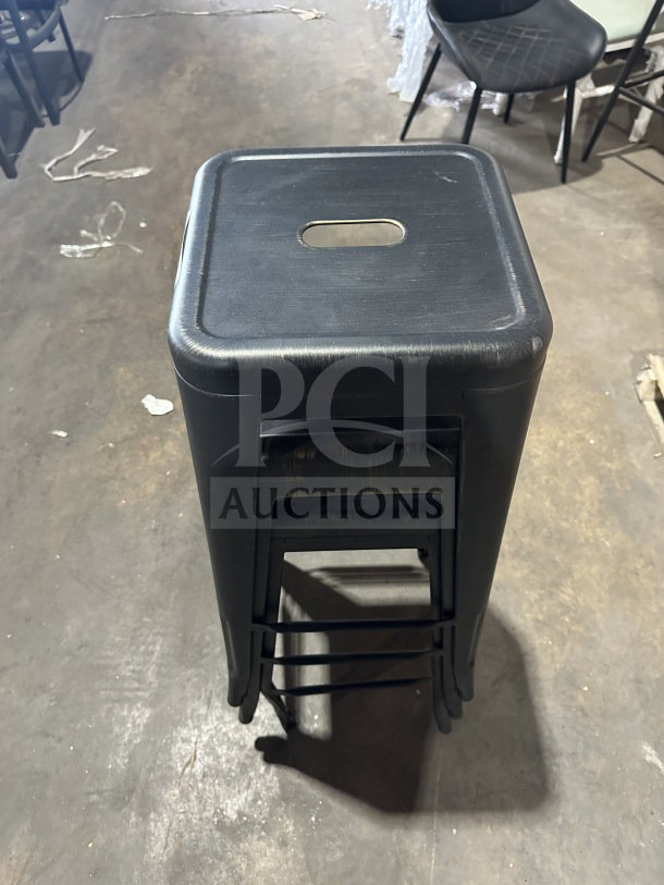 Brand new Astor matte black backless metal bar stool, industrial Tolix-style, stackable, with handle cutout.
