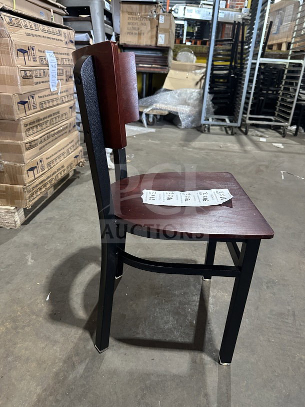 Brand new commercial restaurant chair with mahogany wood back and veneer seat, metal frame; side view on warehouse floor.