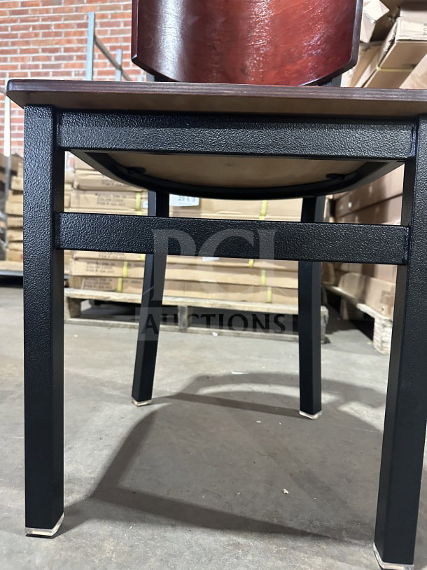 Brand new commercial restaurant chair with mahogany veneer seat and back, metal frame, shown in a warehouse.