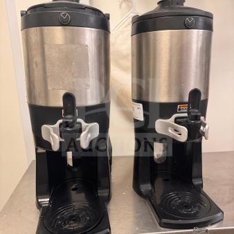 Pair of commercial beverage dispensers with stainless steel and black plastic construction. Visible hot warning labels. Good condition.