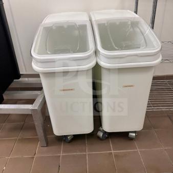 Two white ingredient storage bins with clear lids and casters, labeled "Powdered Sugar," on tile floor.