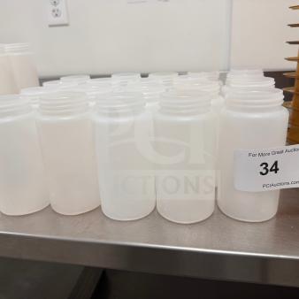 Clear wide mouth squeeze bottles on a metal shelf; clean and ready for use. Auction tag reads "34, QTY 20."