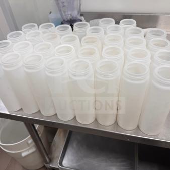 Clear squeeze bottles on a stainless steel table, clean and ready for use, ideal for kitchen or craft purposes.