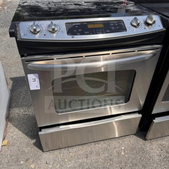 Whirlpool electric range oven with glass cooktop, used condition, visible wear, stainless steel finish, control panel intact.