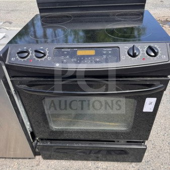 GE residential electric range oven with glass cooktop, used condition, visible wear, includes control knobs and display panel.