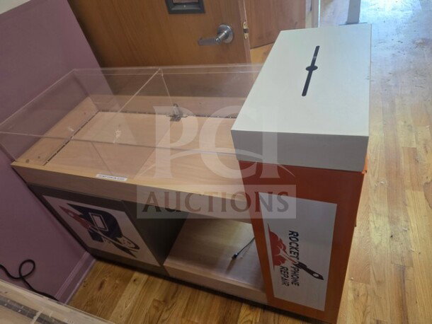 Retail display/checkout counter with glass top, wooden shelves, and Rocket Phone Repair branding. Good condition.
