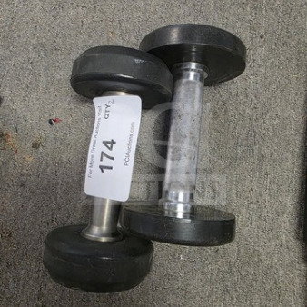 Lot of 2 black dumbbell weights with metal handles, auction tag marked 174, on concrete floor.