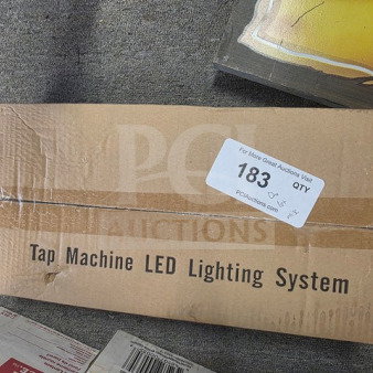 Cardboard box labeled "Tap Machine LED Lighting System" with auction tag "183." Box shows slight wear.