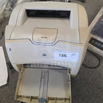 Lot of 2 HP printers, off-white, visible front paper tray open, label reads "186 QTY". Used condition, some scuffs.