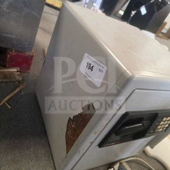Gray safe with keypad, noticeable rust on side, item tag "194." Combination unknown.