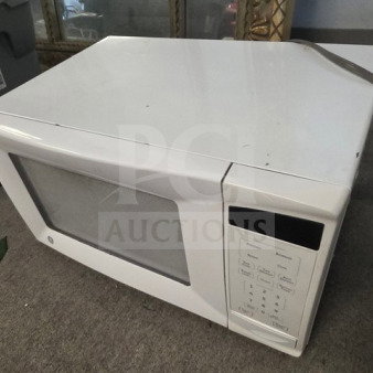 White microwave with digital touchpad and turntable, showing some wear. Great for kitchens. Brand not visible.