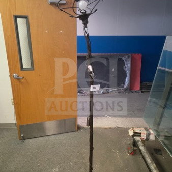 Tall vintage floor lamp with intricate wrought iron design, single bulb holder. Base shows signs of wear, no visible shade.