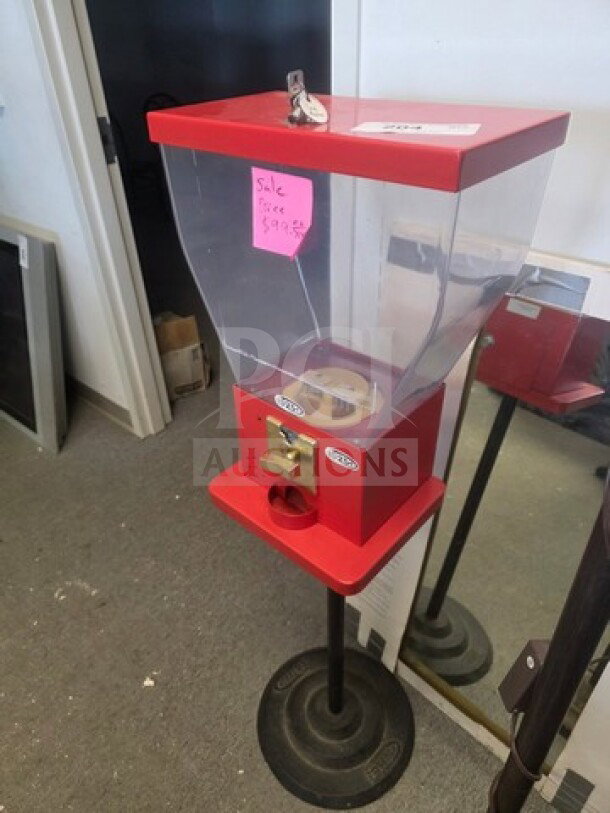 Red gumball machine on stand, clear acrylic globe, secure lock, in used condition, sale price tag $99.99.