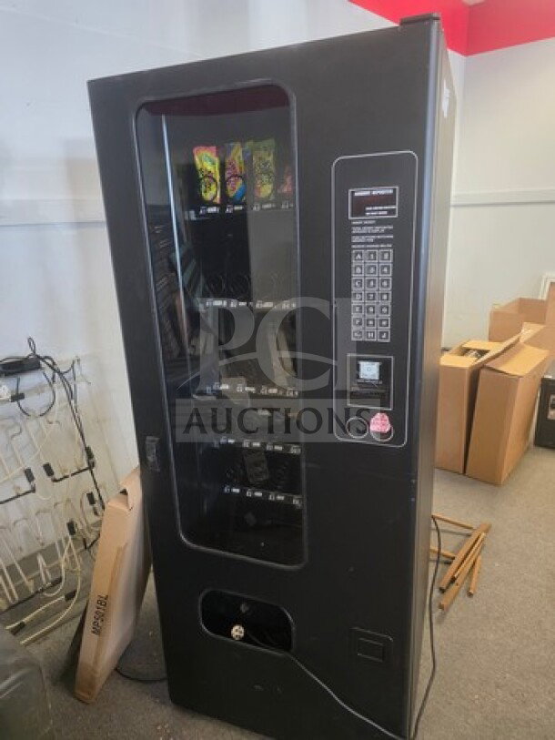 Black vending machine with keypad and display window. Unknown working condition. Sold as is.