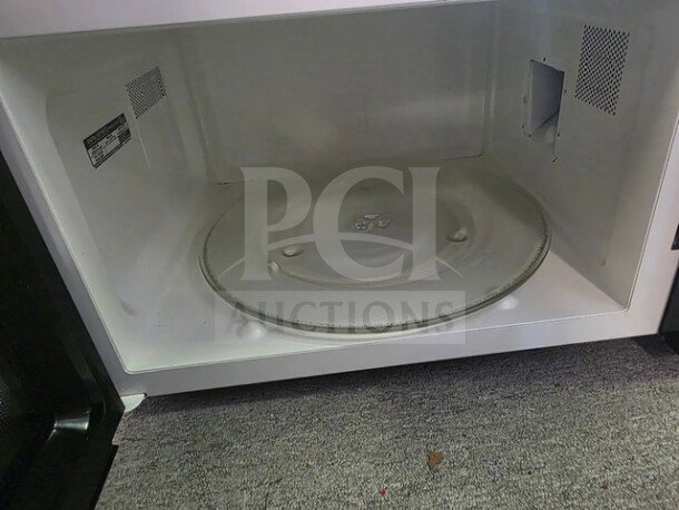 Interior view of a microwave with a glass turntable. Unknown working condition. Sold as is.