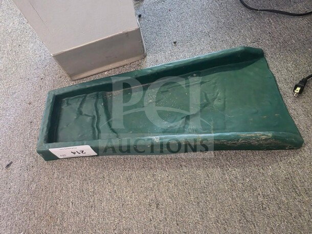 Green gutter splash block, rectangular, with signs of wear. Label marked "214" visible on side. Suitable for water drainage.