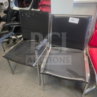 Lot of 2 office chairs with metal frames and black cushions; visible wear and specific tag numbered 223 on one chair.