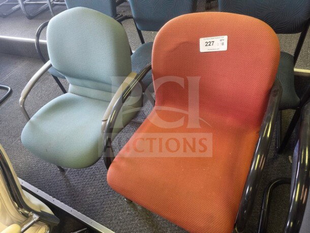 Lot of 2 office chairs: one red, one green. Padded seats, black armrests. Good condition. Auction label visible on red chair.