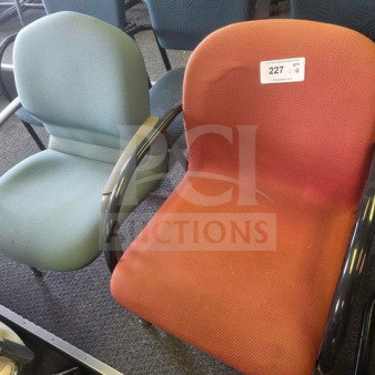 Lot of 2 office chairs: one red, one green. Padded seats, black armrests. Good condition. Auction label visible on red chair.