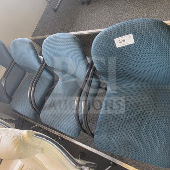 Lot of 4 office chairs with blue fabric upholstery, black metal armrests, and legs. Visible label with number 228. Some wear shown.
