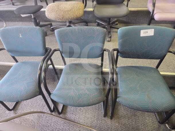 Lot of 3 office chairs with teal patterned fabric and black metal arms, in used condition, tag labeled "229".