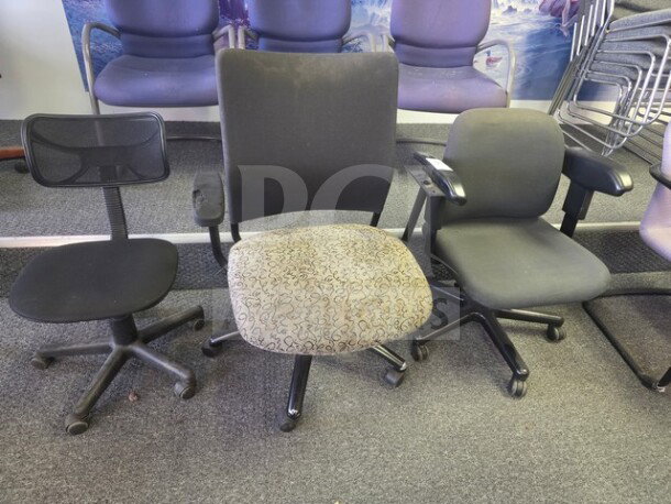 Lot of 3 office chairs showing signs of wear. Includes a mesh-back swivel chair, a patterned seat chair, and a padded armchair.