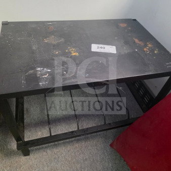 Black work table with metal frame and two-tier shelving, showing signs of wear and surface stains. Label with number "240" attached on top.