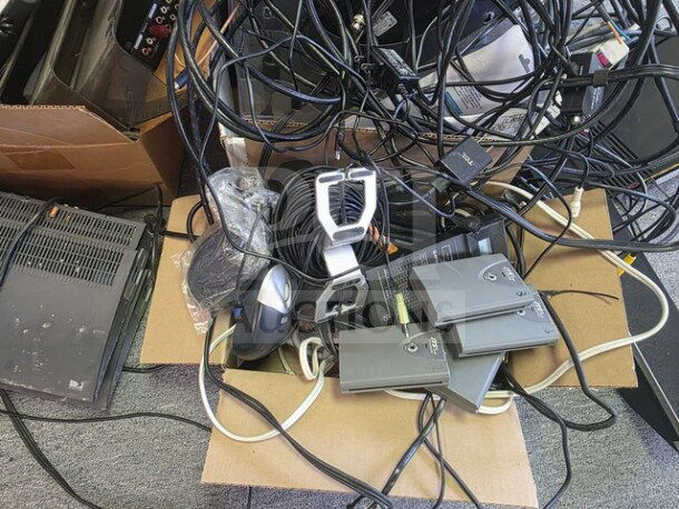 A collection of miscellaneous electronics including cables, power adapters, a mouse, and network devices, showing moderate wear.