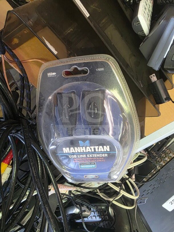 One lot of miscellaneous electronics featuring a packaged Manhattan USB Line Extender 179300, various cables, and remote controls.