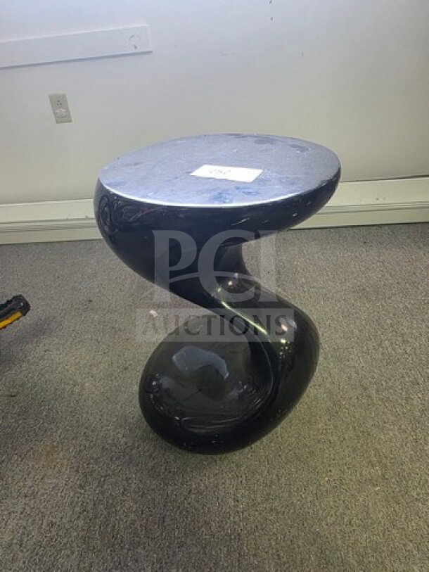 Sculptural black side table with a twisted base design, smooth surface, good condition. White tag on top.