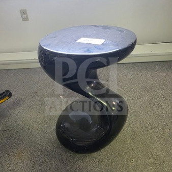 Sculptural black side table with a twisted base design, smooth surface, good condition. White tag on top.