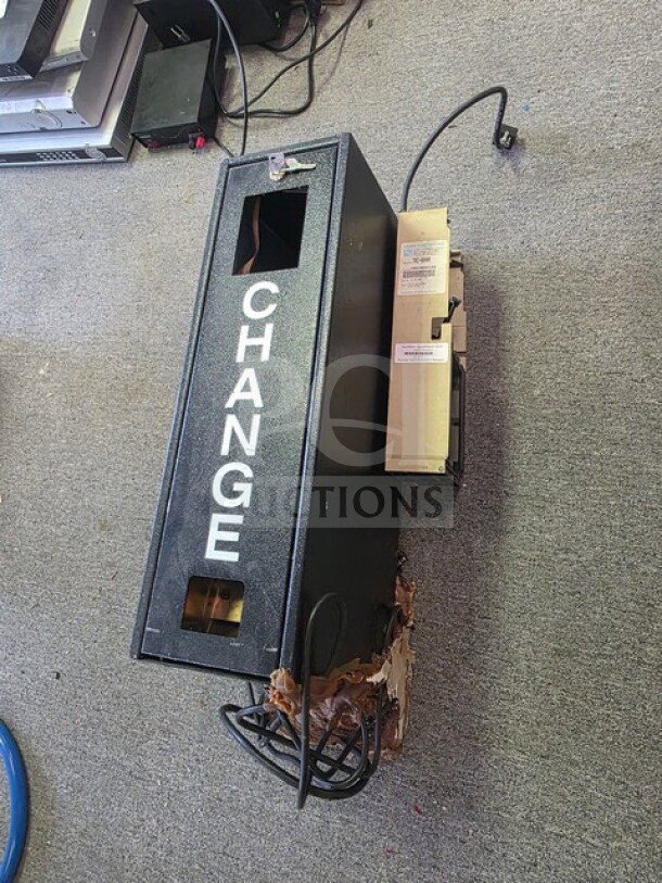 Dollar bill changer machine, black metal casing with "CHANGE" in white text, visible wear and electrical cords.