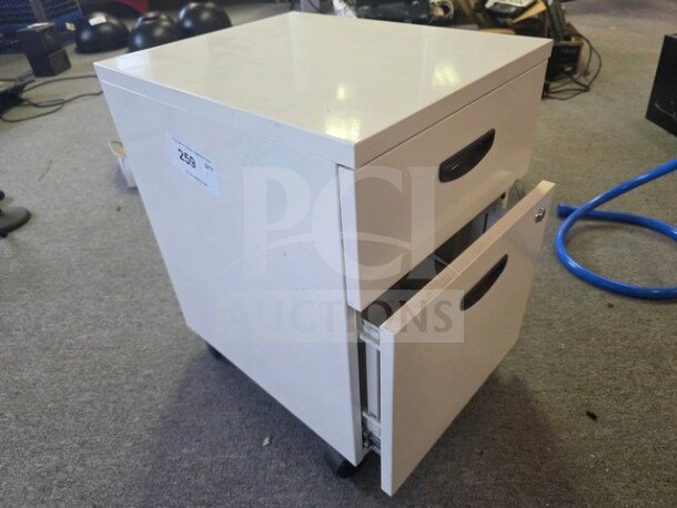 White filing cabinet with two drawers, black handles, and wheels. Item tag reads "259." Good condition.