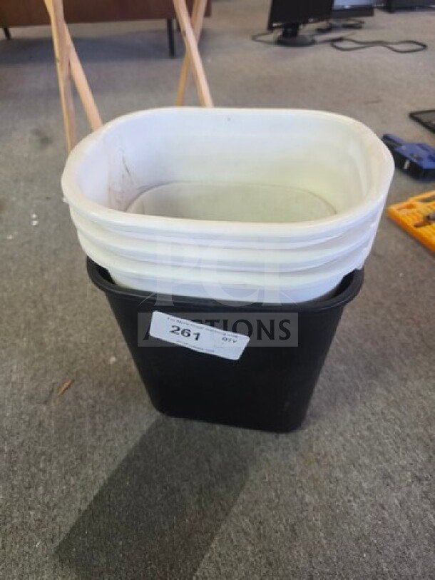 Stacked white and black plastic trash cans, good condition, auction label 261 visible.