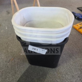 Stacked white and black plastic trash cans, good condition, auction label 261 visible.