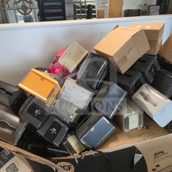 A large collection of assorted napkin dispensers piled in an open cardboard box, various colors and styles visible.
