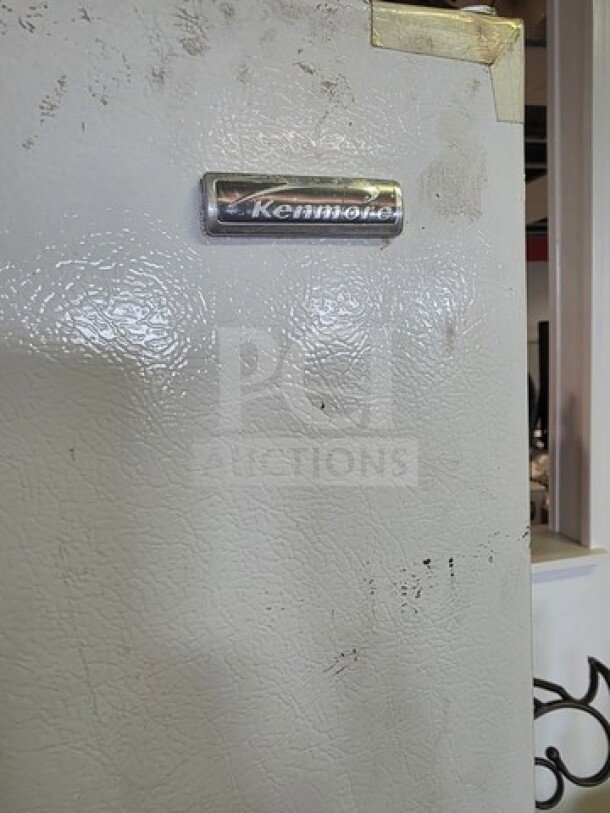 Kenmore Upright Freezer, visible wear, "Kenmore" label, unknown working condition, sold as is.