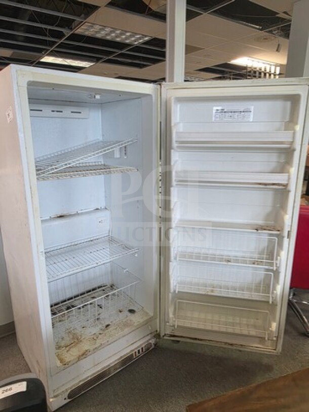 Kenmore Upright Freezer with wire shelving, visible wear and stains, unknown working condition, sold as is.