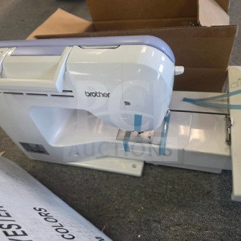 Brother embroidery machine with white body, blue accents, and visible tape. Includes a box labeled "Polyester Embroidery Colors."