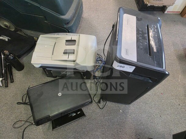 Lot of office equipment: paper shredder, HP fax machine, and black printer. Visible wear, cables included.
