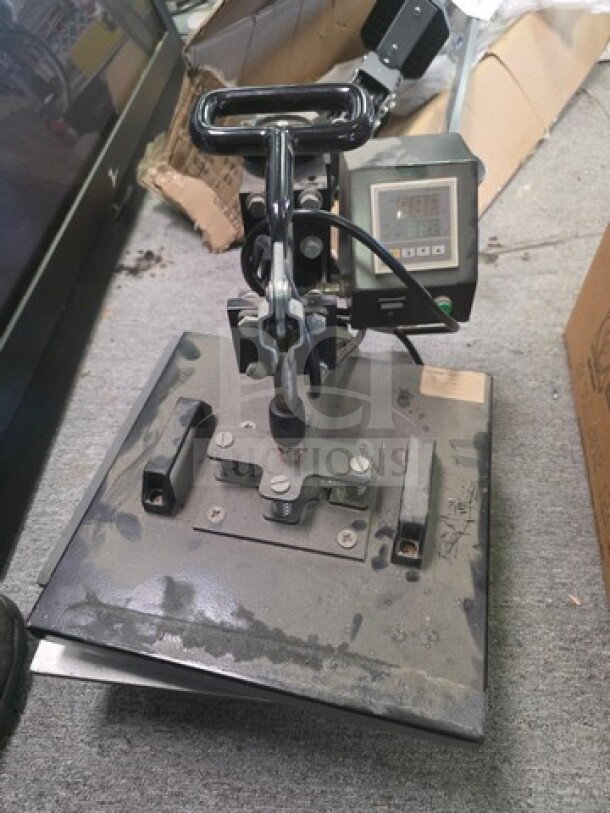 Heat press machine with digital display and adjustable handle, showing signs of wear.