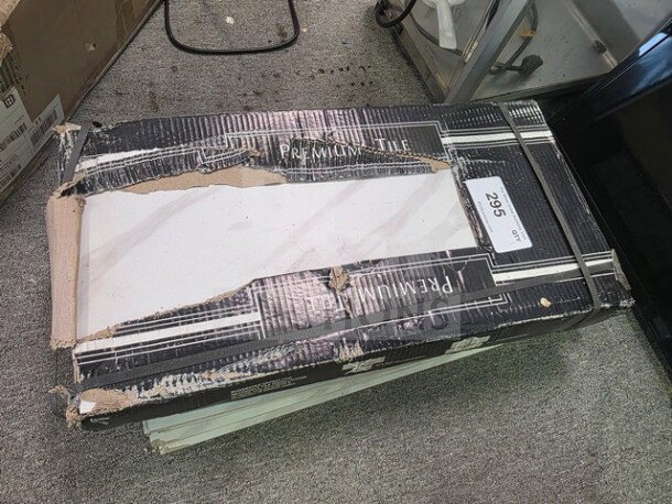 Damaged box of premium tiles, marked lot 295. Sold as is. Some packaging wear visible.