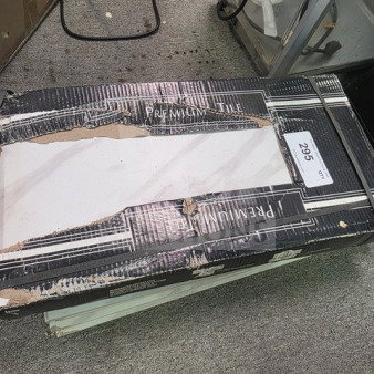 Damaged box of premium tiles, marked lot 295. Sold as is. Some packaging wear visible.