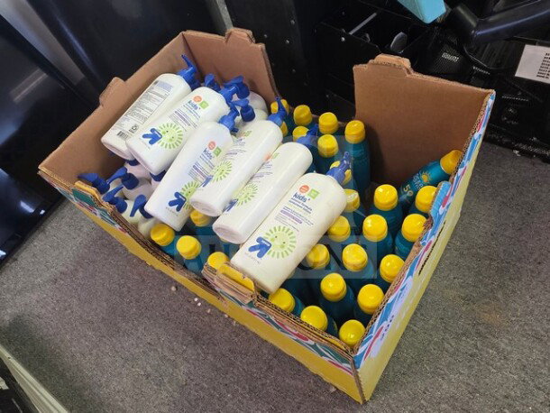 Box containing assorted sunscreen bottles, featuring Up & Up brand. Bottles have white and blue design with yellow caps, varying quantities.