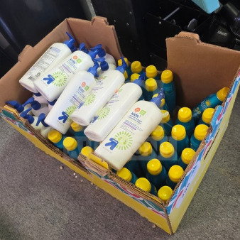 Box containing assorted sunscreen bottles, featuring Up & Up brand. Bottles have white and blue design with yellow caps, varying quantities.