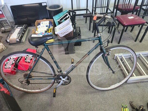 Bridgestone XO-5 hybrid bicycle, green frame, 700c wheels, drop handlebars, visible wear. Suitable for versatile cycling.
